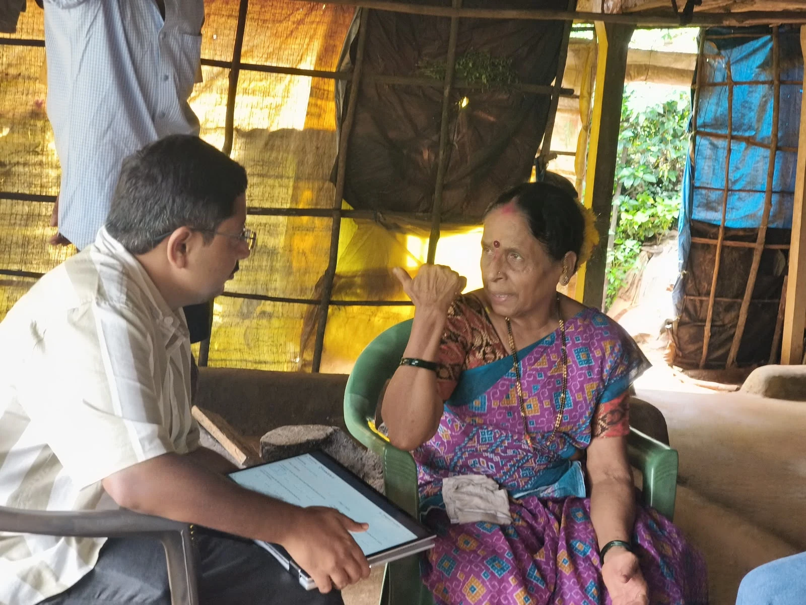 A health camp team member listening to a participant with a tablet at hand