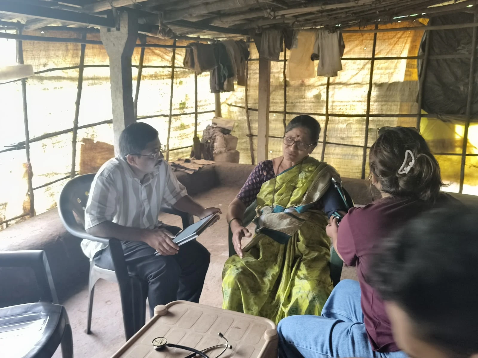 A seated participant speaking with the health camp team while information is recorded on a tablet